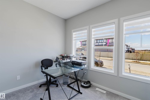 Bright interior space featuring three large windows with white trim, light gray painted walls, and gray carpeting - 343 Edgemont Drive, Edmonton, AB - Indoor Photo Showing Office