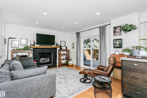 Living area featuring a floor-to-ceiling slate fireplace with a wood mantle, wood-finish flooring, recessed lighting, and a sliding glass door - 17820 57 Avenue, Edmonton, AB - Indoor Photo Showing Living Room With Fireplace