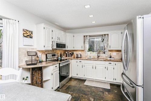 Kitchen featuring white cabinetry, granite countertops, and stainless steel appliances - 17820 57 Avenue, Edmonton, AB - Indoor Photo Showing Kitchen