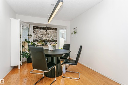 Dining area featuring hardwood flooring, a bay window, and a linear pendant light fixture - 17820 57 Avenue, Edmonton, AB - Indoor Photo Showing Dining Room