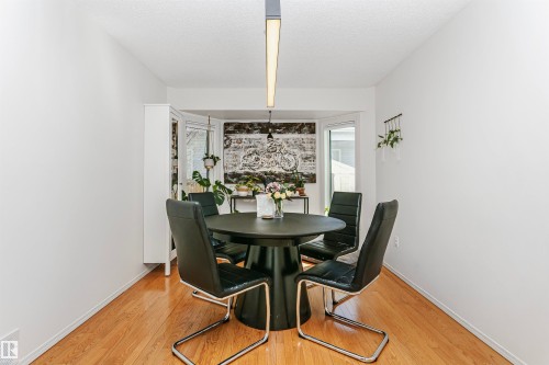 Dining area featuring wood-finish flooring, a contemporary linear light fixture, and a bay window - 17820 57 Avenue, Edmonton, AB - Indoor Photo Showing Dining Room