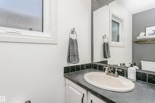 Bathroom vanity with an integrated oval sink, brushed nickel faucet, and a dark stone-look countertop - 17820 57 Avenue, Edmonton, AB - Indoor Photo Showing Bathroom