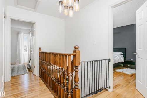 Hallway featuring wood-finish flooring, white walls, and a wood banister with balusters - 17820 57 Avenue, Edmonton, AB - Indoor Photo Showing Other Room