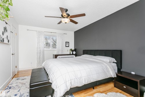 Room featuring wood-finish flooring, a textured white ceiling, and a prominent dark accent wall - 17820 57 Avenue, Edmonton, AB - Indoor Photo Showing Bedroom