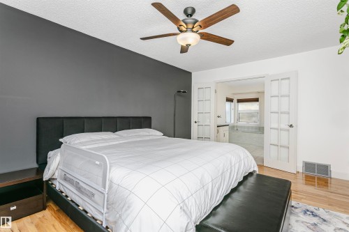 Bedroom with wood-finish flooring, a ceiling fan with integrated lighting, and a textured white ceiling - 17820 57 Avenue, Edmonton, AB - Indoor Photo Showing Bedroom
