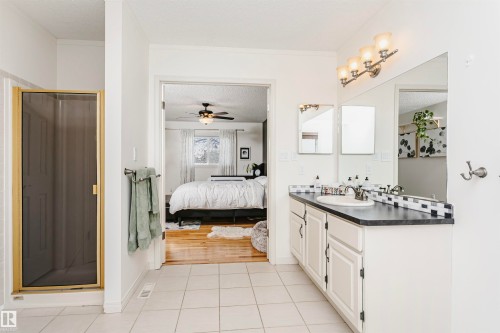 Bathroom featuring a vanity with a dark countertop, an integrated sink, and white cabinetry - 17820 57 Avenue, Edmonton, AB - Indoor