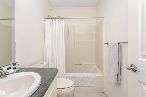 Bathroom featuring a white vanity with an undermount sink, dark countertop, and tiled backsplash - 17820 57 Avenue, Edmonton, AB - Indoor Photo Showing Bathroom