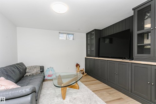 Built-in cabinetry with dark paneling and glass-front upper cabinets, light wood-finish flooring, and a recessed window - 17820 57 Avenue, Edmonton, AB - Indoor Photo Showing Other Room