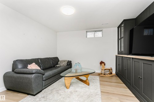 Built-in media cabinetry with glass-front display case, light wood-finish countertop, and dark paneling - 17820 57 Avenue, Edmonton, AB - Indoor Photo Showing Living Room