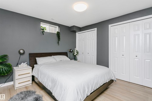 Spacious room featuring light wood-finish flooring, a contemporary ceiling light fixture, and two sets of bi-fold closet doors - 17820 57 Avenue, Edmonton, AB - Indoor Photo Showing Bedroom