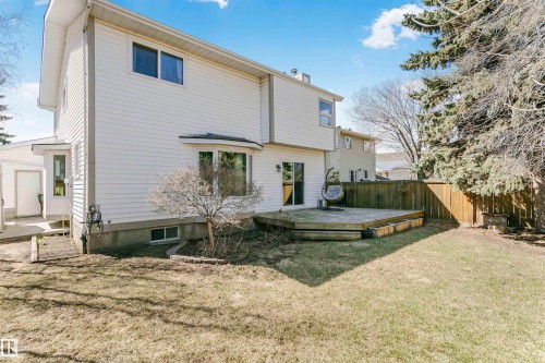 Rear exterior featuring white horizontal siding, a bay window, and a ground-level wood deck - 17820 57 Avenue, Edmonton, AB - Outdoor