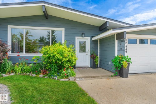 Exterior featuring horizontal siding, a white garage door with transom windows, a concrete driveway, and a front entry door with an adjacent full-lite window - 10339 36A Avenue, Edmonton, AB - Outdoor