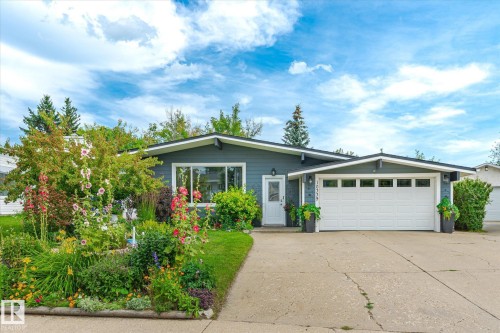 Contemporary ranch-style residence featuring a dark siding exterior, a white garage door with transom windows, and a concrete driveway - 10339 36A Avenue, Edmonton, AB - Outdoor