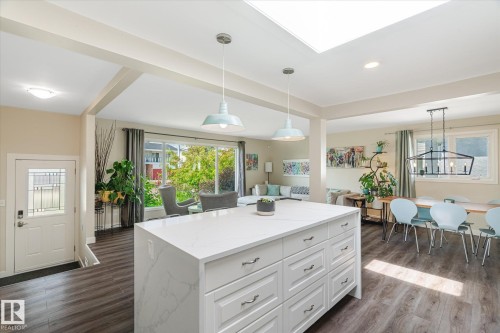 White kitchen island with stone-finish countertop, wood-finish flooring, recessed lighting, and a skylight - 10339 36A Avenue, Edmonton, AB - Indoor