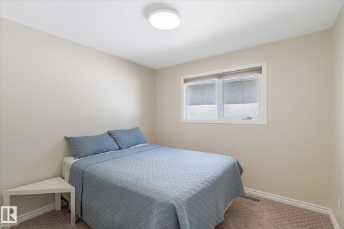 Carpeted room featuring a double window with a roller shade, a ceiling-mounted light fixture, and neutral-toned walls - 10339 36A Avenue, Edmonton, AB - Indoor Photo Showing Bedroom