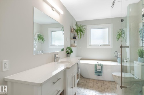 Contemporary bathroom featuring a freestanding tub, glass-enclosed shower, white vanity with integrated sink, rectangular mirror, and dual windows - 10339 36A Avenue, Edmonton, AB - Indoor Photo Showing Bathroom