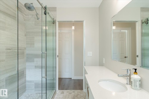 Contemporary bathroom featuring a frameless glass shower enclosure with a rain shower head, large format shower wall tile, and a mosaic tile shower floor - 10339 36A Avenue, Edmonton, AB - Indoor Photo Showing Bathroom