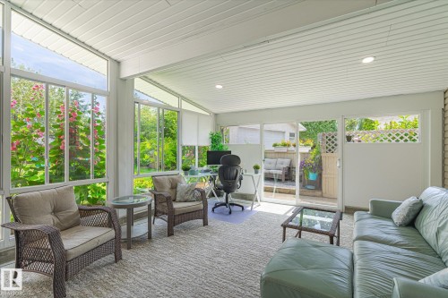 Spacious sunroom featuring extensive window panels, textured carpeting, recessed lighting, and a sliding glass door providing exterior access - 10339 36A Avenue, Edmonton, AB - Outdoor With Deck Patio Veranda With Exterior