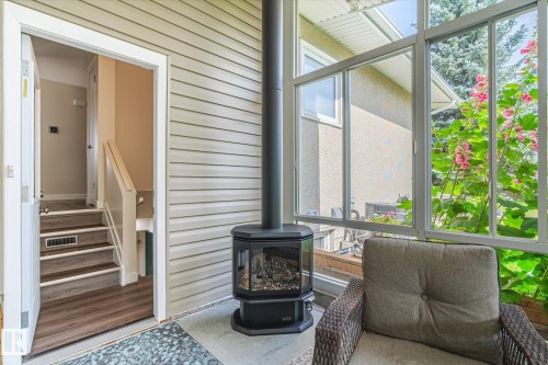 Enclosed sunroom featuring a freestanding fireplace, extensive window panels, and horizontal siding - 10339 36A Avenue, Edmonton, AB - Indoor With Fireplace