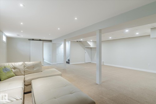Expansive lower-level space featuring recessed lighting, light-toned carpeting, a barn door entry, and a window for natural light - 10339 36A Avenue, Edmonton, AB - Indoor