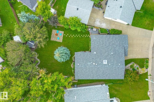 Expansive green lawn featuring mature trees and a dedicated fire pit area with stone pavers - 10339 36A Avenue, Edmonton, AB - Outdoor