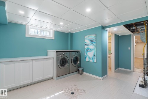 Laundry area featuring integrated white cabinetry with a light-toned countertop, stainless steel washer and dryer units, and recessed lighting - 10339 36A Avenue, Edmonton, AB - Indoor Photo Showing Laundry Room