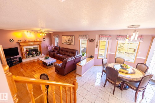 Living room and dining area featuring hardwood flooring, a fireplace with a wood mantle, an overhead ceiling fan, and white tiled flooring in the dining space - 5736 161 Avenue, Edmonton, AB - Indoor With Fireplace