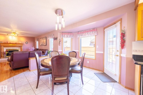 Open-concept dining area featuring tile flooring, a modern chandelier, and bay windows - 5736 161 Avenue, Edmonton, AB - Indoor Photo Showing Dining Room With Fireplace
