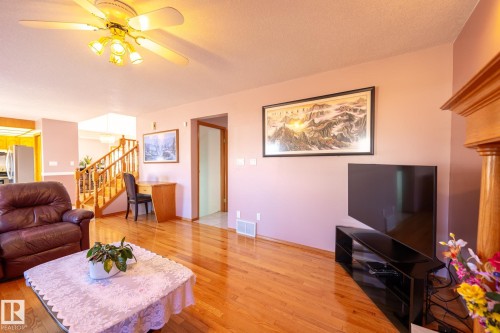 Bright living space with wood-finish flooring, a ceiling fan with integrated lighting, and a built-in wooden fireplace surround - 5736 161 Avenue, Edmonton, AB - Indoor Photo Showing Living Room