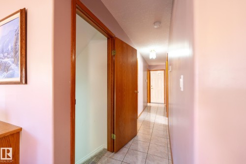 Hallway featuring ceramic tile flooring, wood-finish doors, and a ceiling-mounted light fixture - 5736 161 Avenue, Edmonton, AB - Indoor Photo Showing Other Room