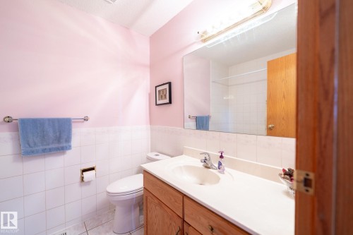 Bathroom featuring a vanity with wood-finish cabinetry, a white countertop, and an integrated sink with a chrome faucet - 5736 161 Avenue, Edmonton, AB - Indoor Photo Showing Bathroom
