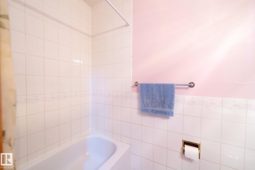 Bathtub surrounded by white square wall tiles with a decorative border - 5736 161 Avenue, Edmonton, AB - Indoor Photo Showing Bathroom