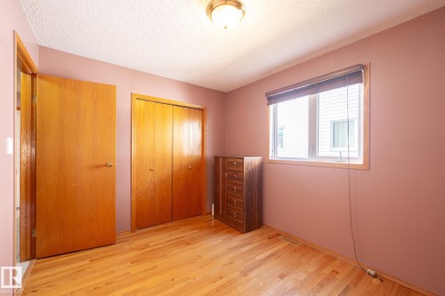 Natural wood-finish flooring with a double-door closet, a single window with blinds, and a ceiling-mounted light fixture - 5736 161 Avenue, Edmonton, AB - Indoor