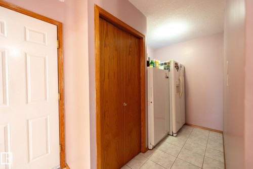 Hallway featuring a white paneled door with wood trim, a wood-finish bi-fold door, and light-toned tile flooring - 5736 161 Avenue, Edmonton, AB - Indoor Photo Showing Other Room