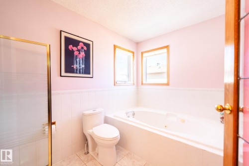 Full bathroom featuring a built-in jetted tub, a separate shower enclosure with a gold-toned frame, and a white toilet - 5736 161 Avenue, Edmonton, AB - Indoor Photo Showing Bathroom