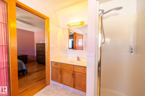 Full bathroom featuring a single vanity with wood cabinetry, a white countertop, and an integrated sink, complemented by a large mirror and overhead lighting - 5736 161 Avenue, Edmonton, AB - Indoor Photo Showing Bathroom