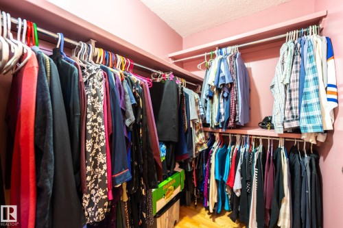 Walk-in closet featuring built-in shelving, multiple hanging rods, and wood-finish flooring - 5736 161 Avenue, Edmonton, AB - Indoor With Storage