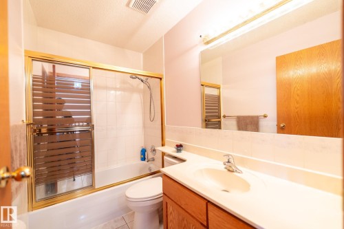 Bathroom featuring a white bathtub, gold-framed glass shower enclosure, and white tiled walls - 5736 161 Avenue, Edmonton, AB - Indoor Photo Showing Bathroom