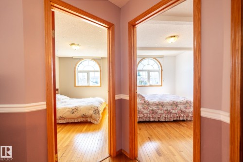 Rooms featuring wood-finish flooring, arched windows, and ceiling-mounted light fixtures - 5736 161 Avenue, Edmonton, AB - Indoor Photo Showing Bedroom