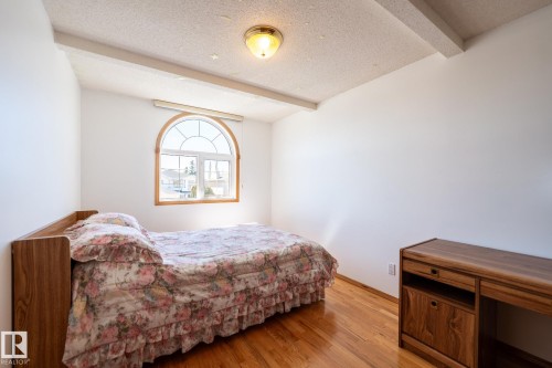 Hardwood flooring complements white walls and ceiling beams - 5736 161 Avenue, Edmonton, AB - Indoor Photo Showing Bedroom