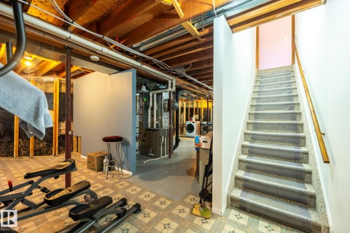 Finished basement area featuring exposed ceiling joists, utility space, and a carpeted staircase with a wood handrail - 5736 161 Avenue, Edmonton, AB - Indoor Photo Showing Basement