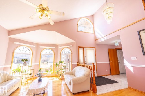 Vaulted ceiling living area featuring multiple arch-top windows, wood-finish flooring, and a decorative chandelier - 5736 161 Avenue, Edmonton, AB - Indoor Photo Showing Living Room