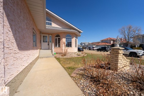 Stucco exterior with arched transom window, bay window with arched tops, concrete walkway, and brick-clad light pillar - 5736 161 Avenue, Edmonton, AB - Outdoor