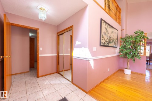Entryway featuring a tiled floor, wood-finish flooring, wood trim, mirrored closet doors, and an overhead light fixture - 5736 161 Avenue, Edmonton, AB - Indoor Photo Showing Other Room