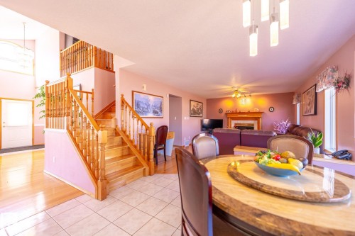 Open-concept living area featuring a prominent wooden staircase with balusters, wood-finish flooring, and a tiled entry - 5736 161 Avenue, Edmonton, AB - Indoor Photo Showing Dining Room