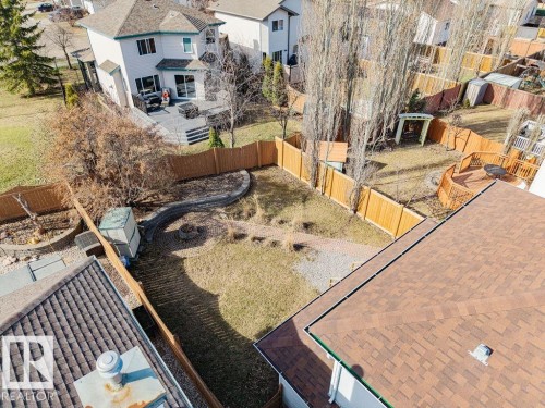Expansive backyard featuring a manicured lawn, full perimeter fencing, a decorative paved pathway, and a built-in fire pit - 7 Doucette Place, St. Albert, AB - Outdoor