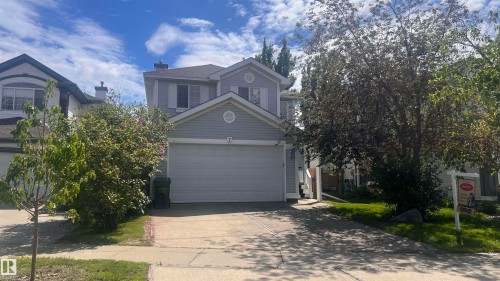 Two-story siding exterior featuring a two-car garage, concrete driveway, and mature landscaping - 7 Doucette Place, St. Albert, AB 