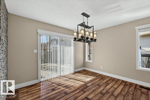 Spacious room featuring wood-finish flooring and a stone accent wall - 10 Erickson Close, St. Albert, AB - Indoor Photo Showing Other Room