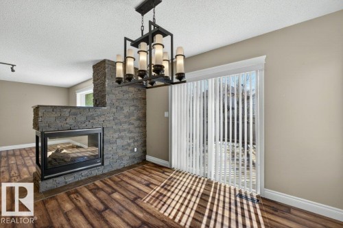 Expansive two-sided fireplace featuring a stacked stone surround and hearth - 10 Erickson Close, St. Albert, AB - Indoor With Fireplace