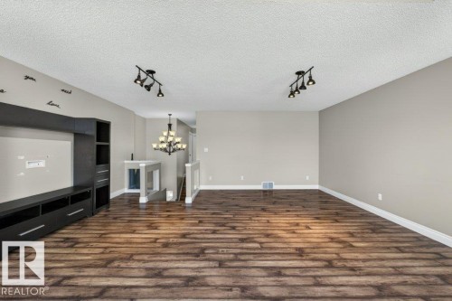 Expansive room featuring wood-finish flooring, a built-in entertainment unit, and track lighting - 10 Erickson Close, St. Albert, AB - Indoor Photo Showing Other Room